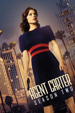 Hayley Atwell in a navy dress in front of the Hollywood hills and a Los Angeles hotel sign.
