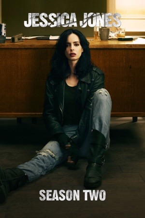 Krysten Ritter sitting alone on the floor of a bare room, lit blue.